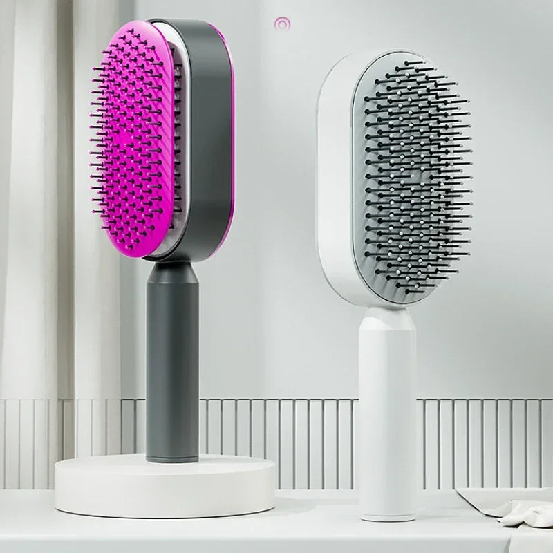 Zwei moderne selbstreinigende Haarbürsten in Pink-Schwarz und Weiß-Grau, aufrecht präsentiert auf Podesten in einem minimalistischen Raum. Design-Haarbürsten mit abgerundeten Borsten für sanftes Entwirren und schonende Haarpflege.